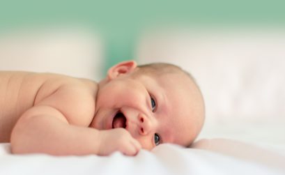 Baby lachend auf der Decke liegend